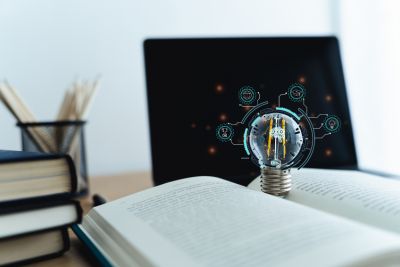 Open book and centered lightbulb, glowing with electronic graphics