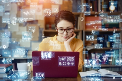 Digital symbols float around a woman at a computer.