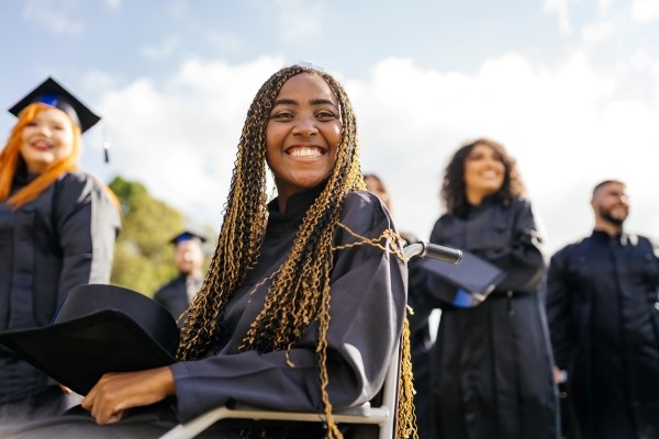 An African American graduate sitting in her wheelchair and smiling.

